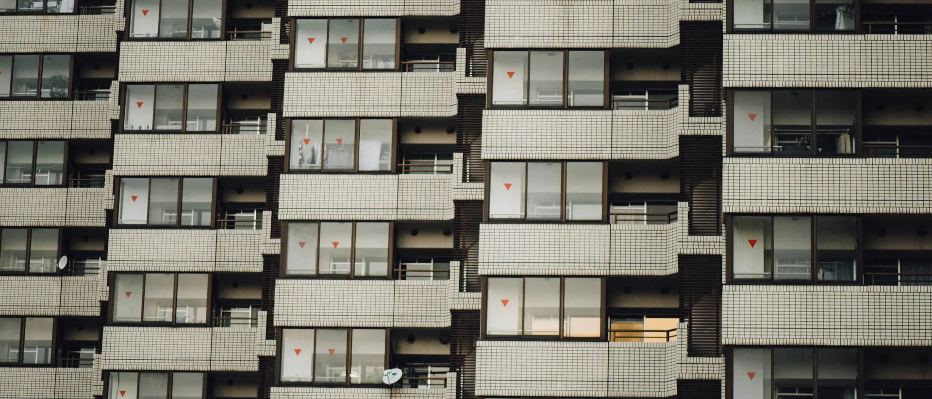 A multi-storey apartment facade with stacked balconies, seen from below.